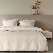 full bed: Armance natural cotton duvet cover with ruffled edges, styled on a bed with matching ruffled pillows